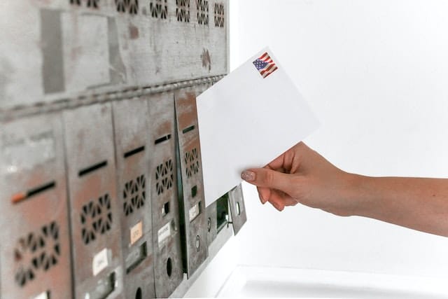 A hand putting a letter into a mail box